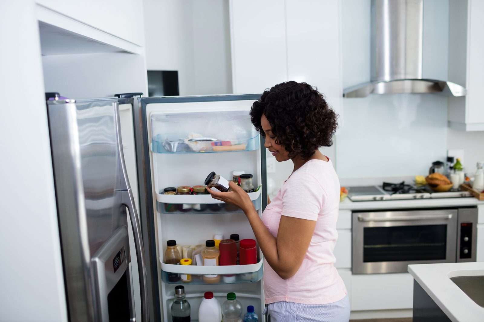 A homeowner checking food and temperature in a smart fridge